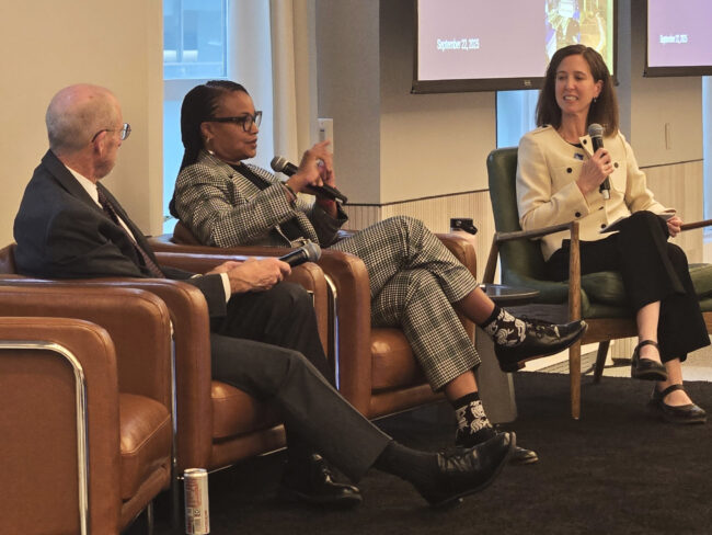 Three panelists seated on stage