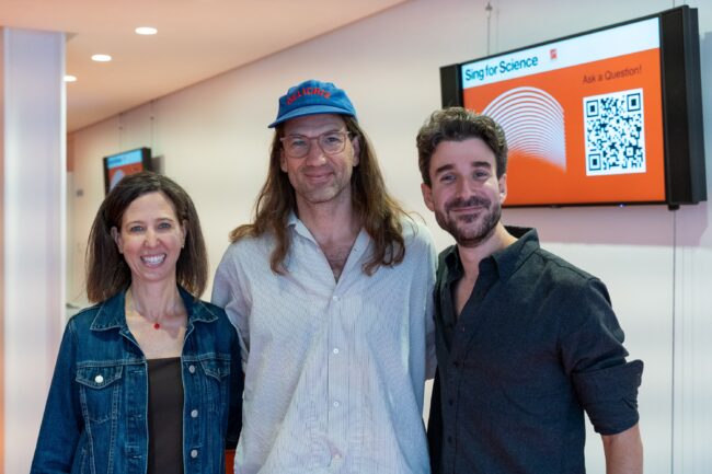 A close up photo of Alexis Abramson, Sing for Science host Matt Whyte, and Adam Met.