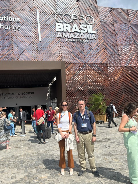 Jeff Schlegelmilch and Alexis Abramson in front of a building that says COP30,