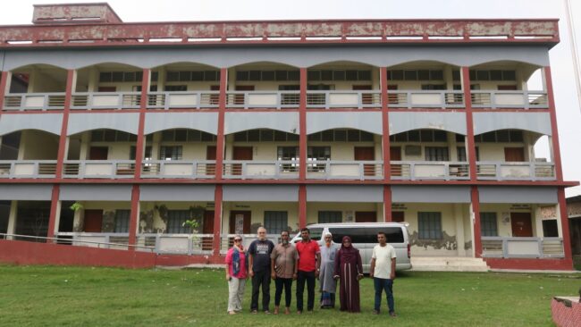 Tim peneliti berfoto di depan sekolah