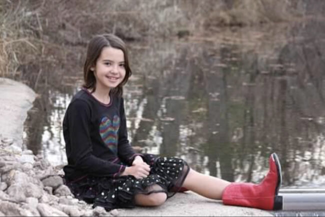 Seorang gadis bersepatu merah berpose di depan sungai