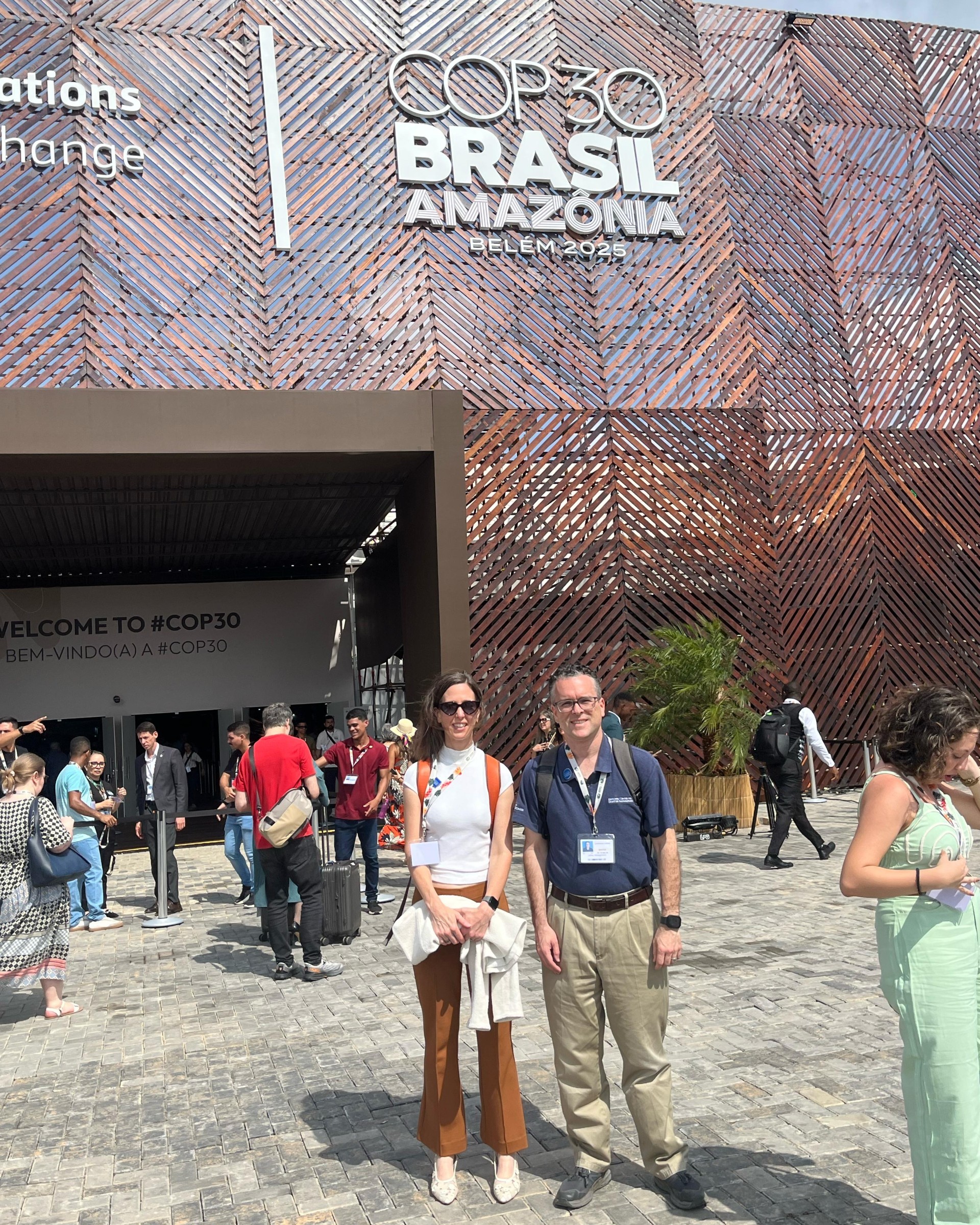 Jeff Schlegelmilch, director of the National Center for Disaster Preparedness, and Alexis Abramson, dean of the Columbia Climate School, in front of a pavillon at COP30.