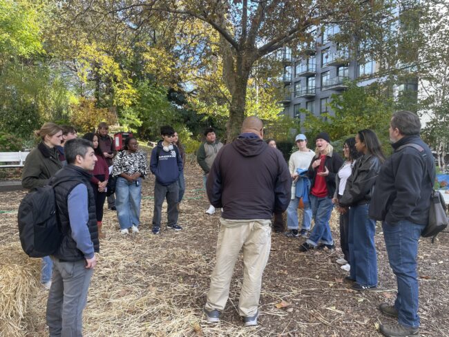 Students in the Building Climate Justice: Co-Creative Coastal Resilience Planning course outside, among some trees