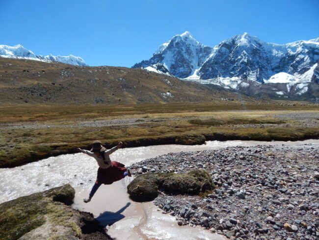 Seorang gadis muda melompati sungai di Dataran Tinggi Peru