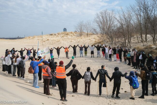 Community members in Coney Island Link arms on the beach
