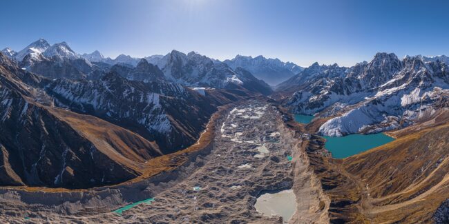 Snowy mountain range with a glacier-filled valley and turquoise alpine lakes