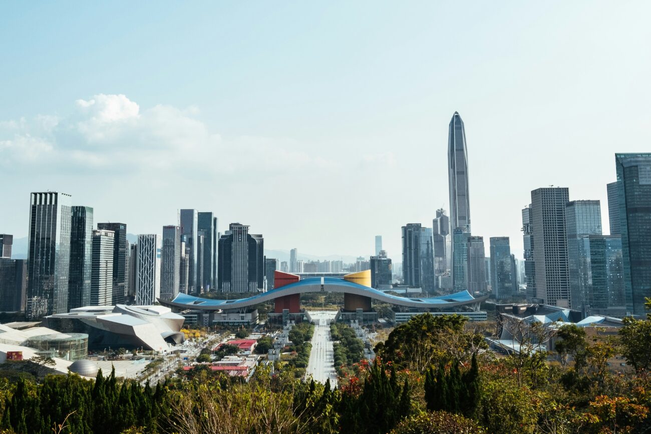 City skyline with a tall skyscraper and a large blue-roofed convention center in the foreground