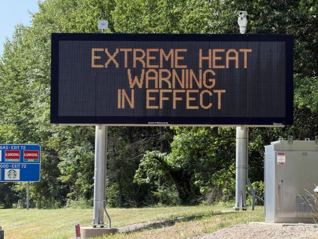 Sign displaying "Excessive Heat Warning In Effect" during triple-digit heat along the highway