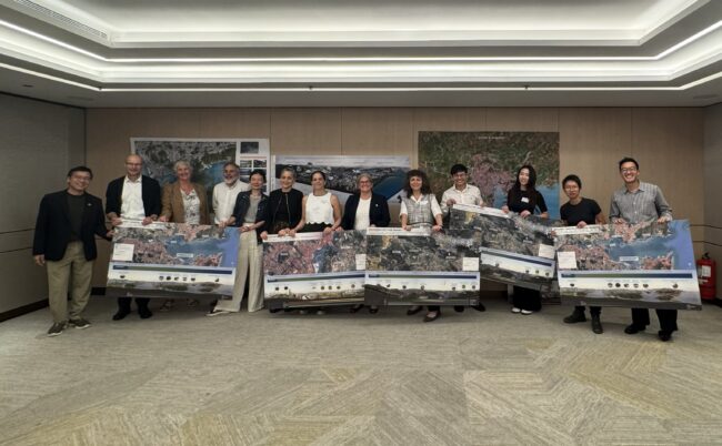 Group of people holding large map posters during a presentation in a conference room