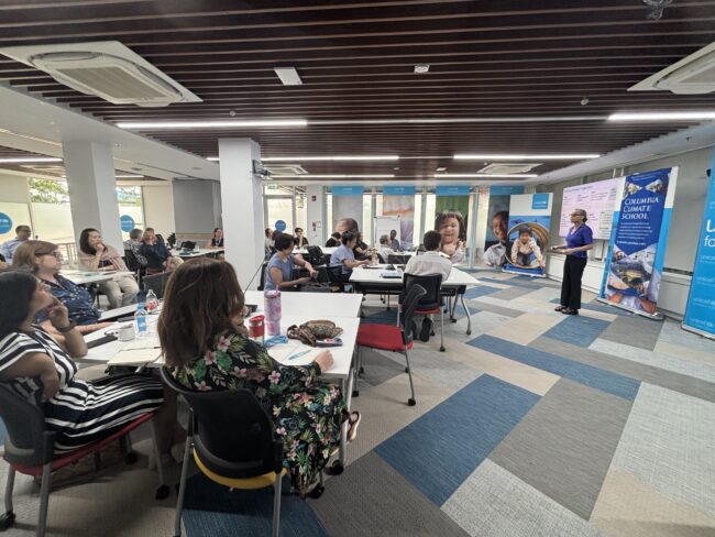 People attending a presentation in a conference room, with UNICEF and Columbia Climate School banners at the front