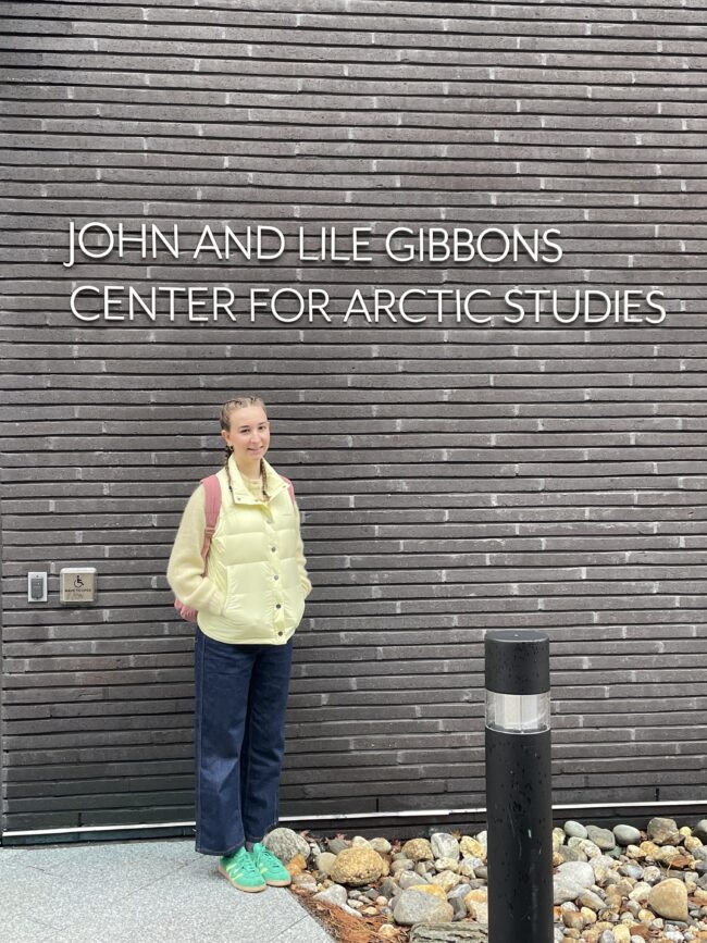 Person standing beneath a sign reading “John and Lile Gibbons Center for Arctic Studies.”