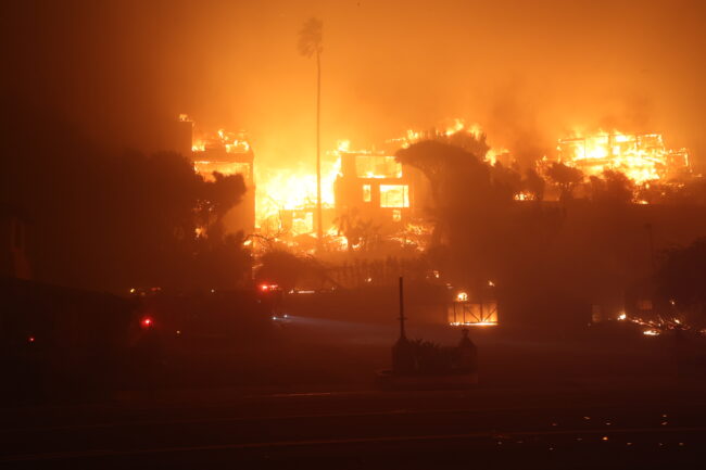 Buildings engulfed in a large nighttime fire, with flames and smoke lighting the sky