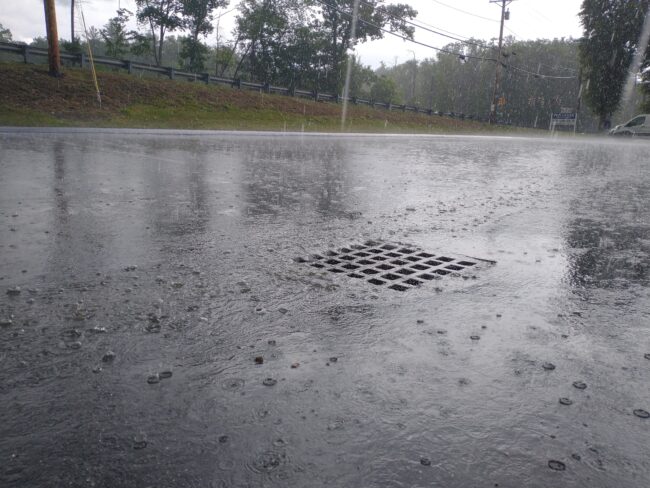 A stormdrain receiving water input during a high-precipitation storm in Massachusetts.