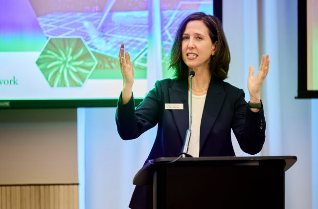 Alexis Abramson with her hands up, in front of a screen