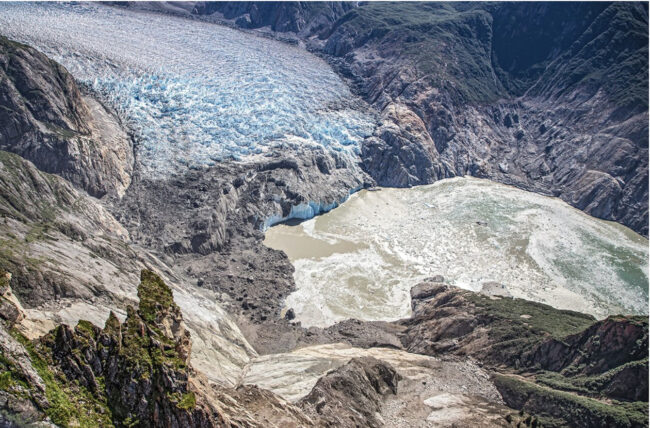 A photo of the Tracy Arm Fjord post tsunami, showing the landslide scar and zone where vegetation was stripped by the tsunami.
