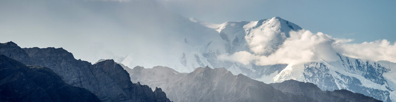 Photograph of mountain landscape from a high vantage point showing a snow-capped peak in the distance.