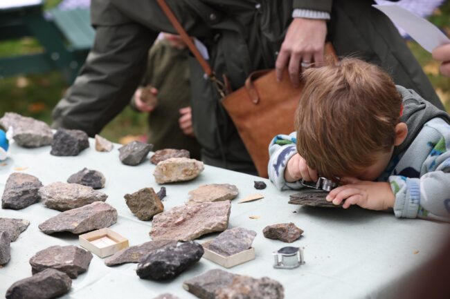 Child looks at rock through magnifying glass
