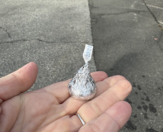 A hand holding a Hershey's kiss candy