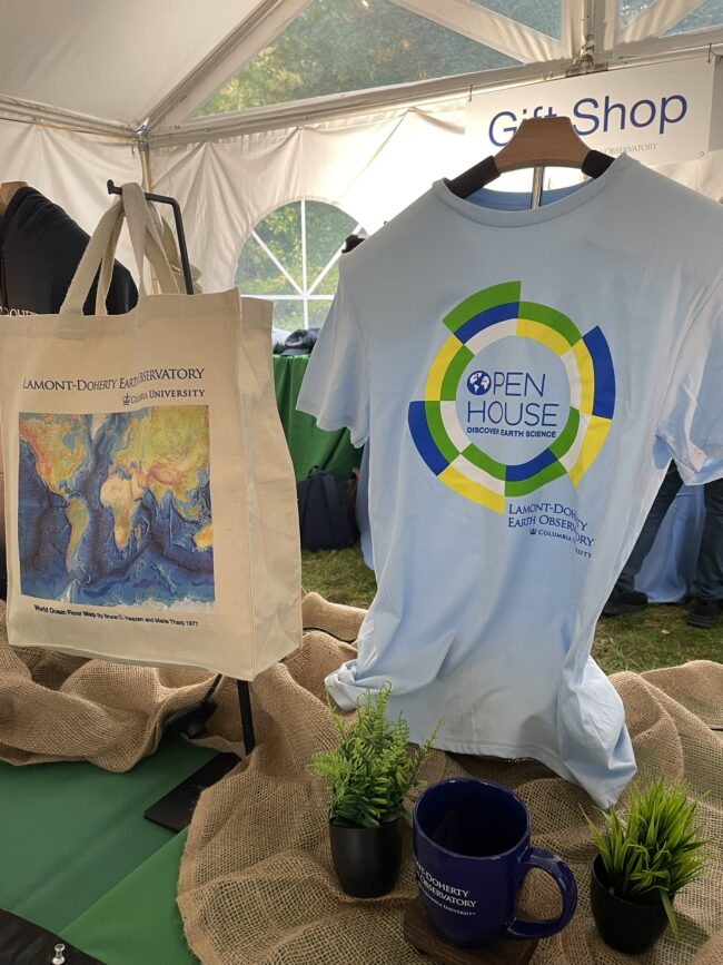 Gift shop display featuring a Lamont-Doherty Earth Observatory Open House T-shirt, world ocean floor map tote bag, and mug