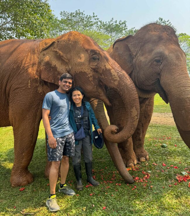 The author standing in front of two elephants, his arm around conservationist Lek Chailert 