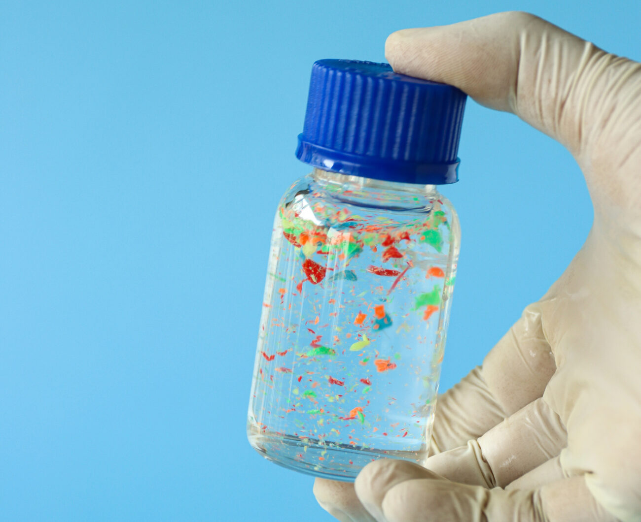 Microplastics in a test tube against a blue background